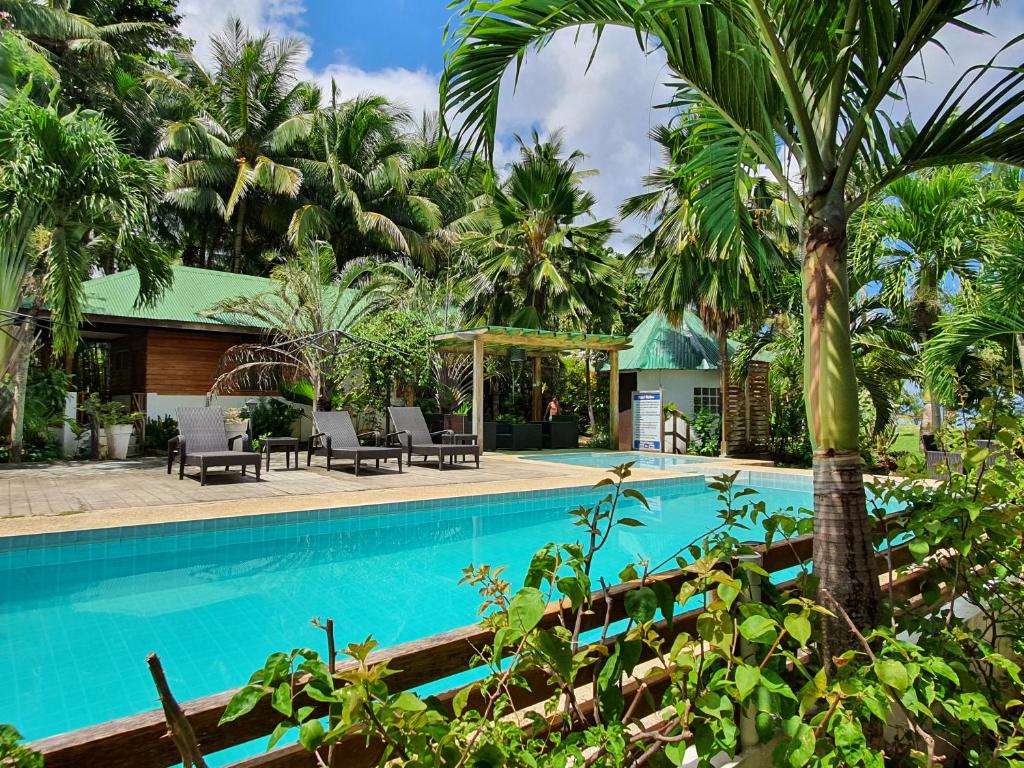 a swimming pool with palm trees and a house at Charisma Beach Resort in Siquijor
