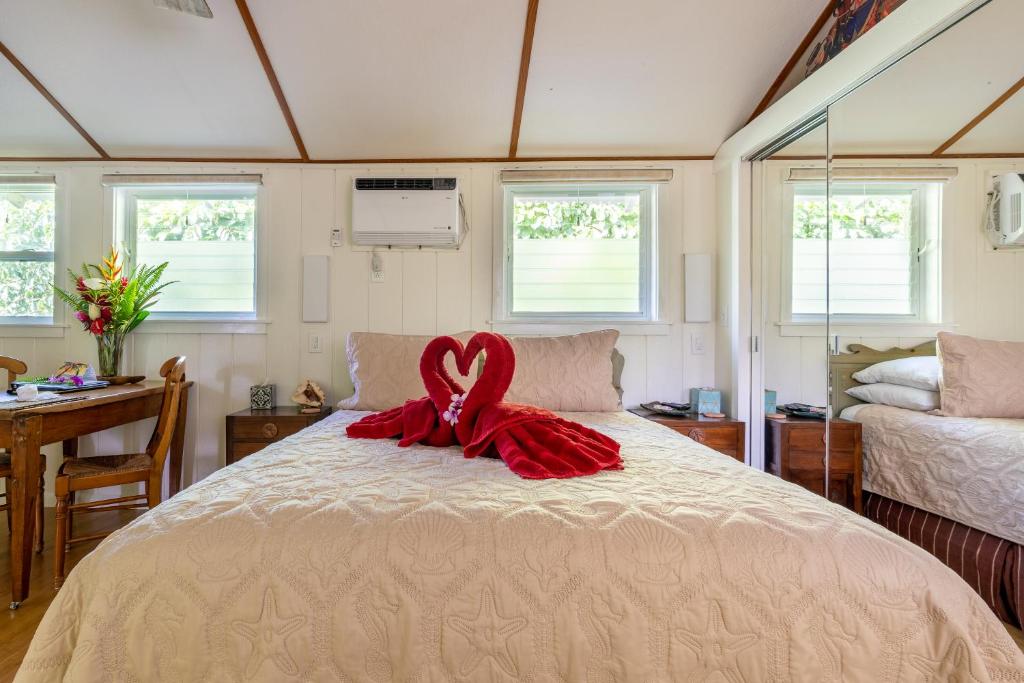 a bedroom with a bed with a red ribbon on it at Fern Grotto Inn in Kapaa
