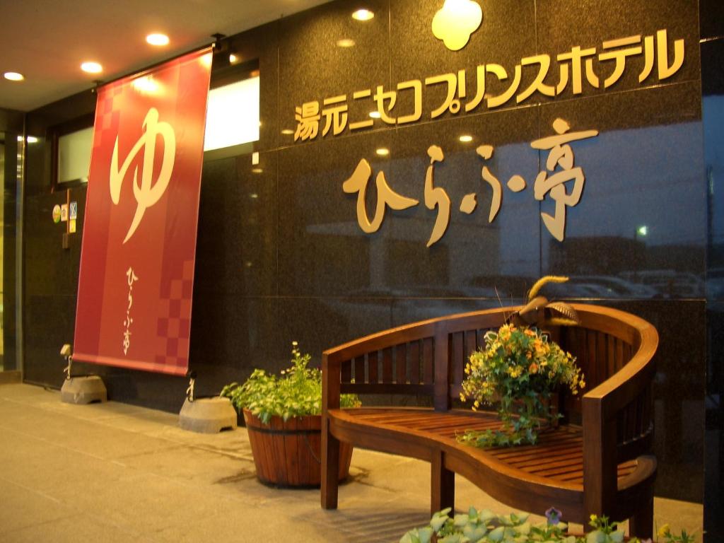 Niseko Prince Hotel Hirafutei في نيسيكو: كرسي خشبي جالس خارج مبنى عليه ورد