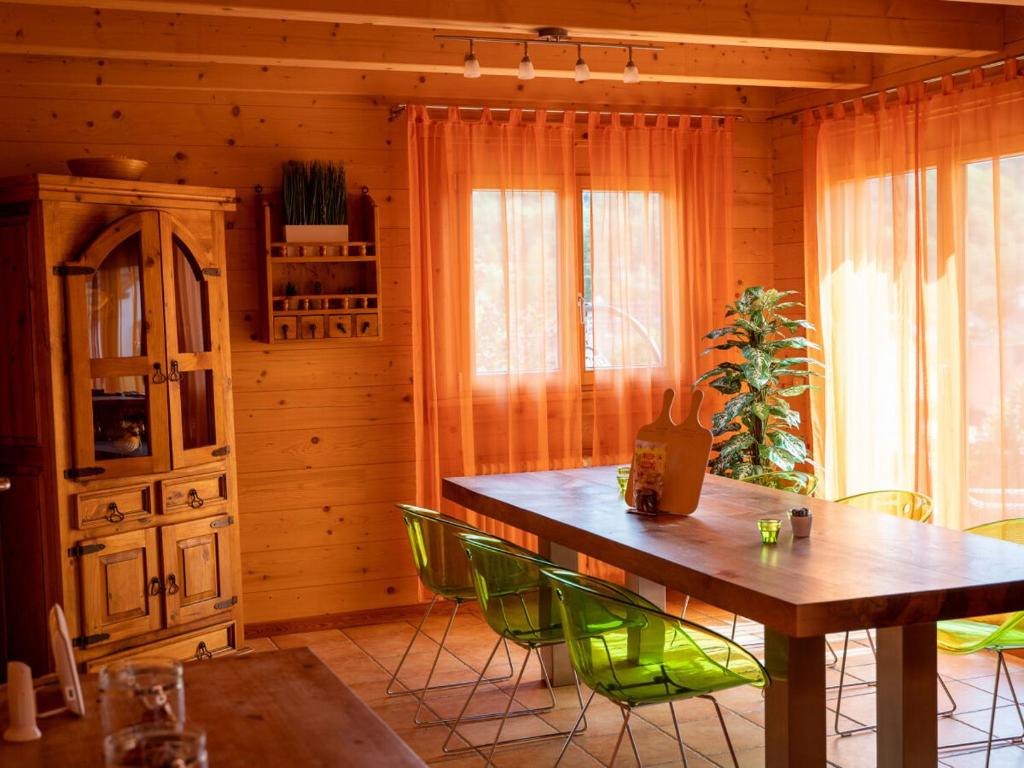 a dining room with a wooden table and green chairs at Ferienhaus Friedrichsblick in Lug