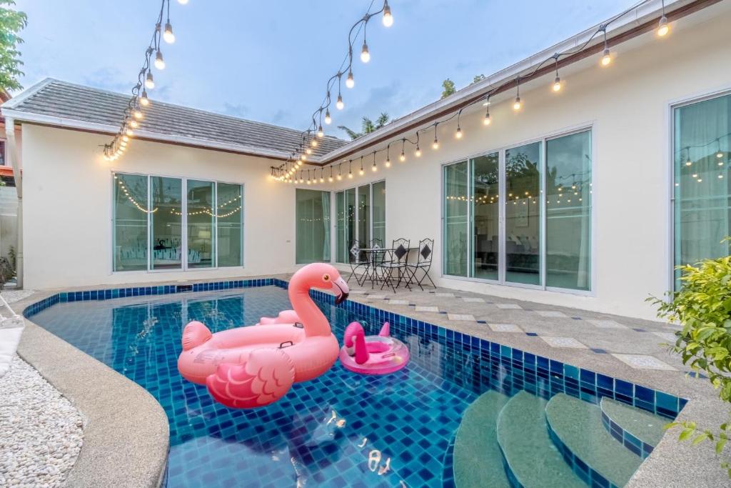 two pink inflatable flamingos in the swimming pool of a house at Peacock Pool Villa in Nong Prue