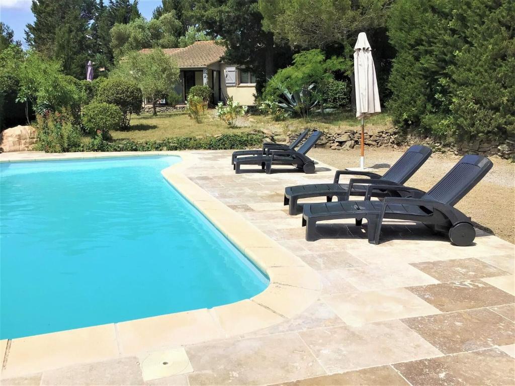 un gruppo di sedie e un ombrellone accanto alla piscina di Charming holiday home with private pool a Montbrun-des-Corbières