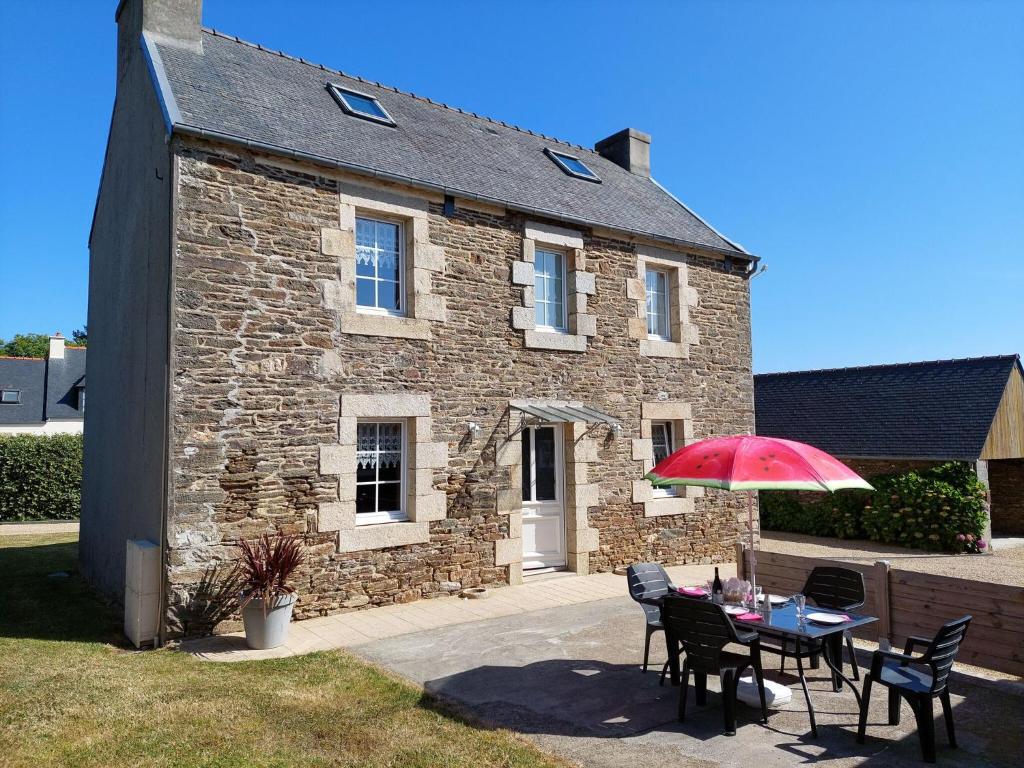 a table with a red umbrella in front of a stone house at Cottage, Plouenan in Plouénan