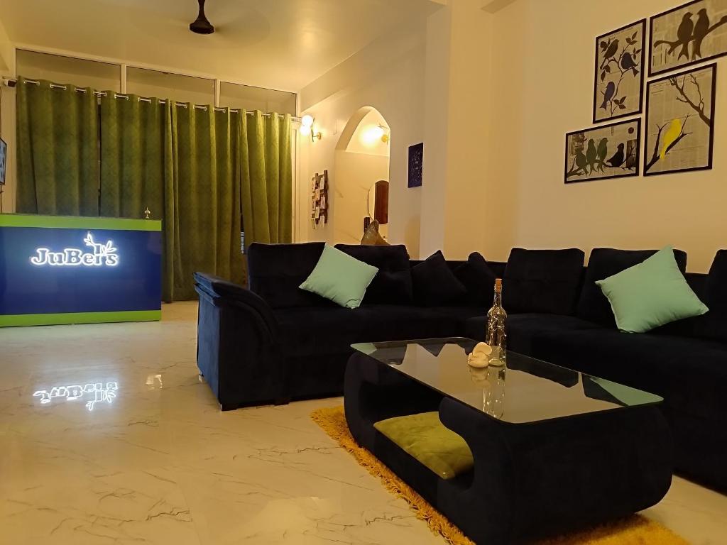 Jubels Homestay في غاواهاتي: غرفة معيشة مع أريكة سوداء وطاولة
