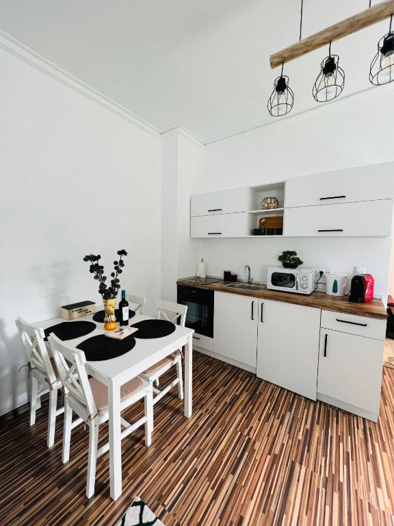 cocina con armarios blancos, mesa y sillas en Apartament in regim hotelier King Medias, en Mediaş