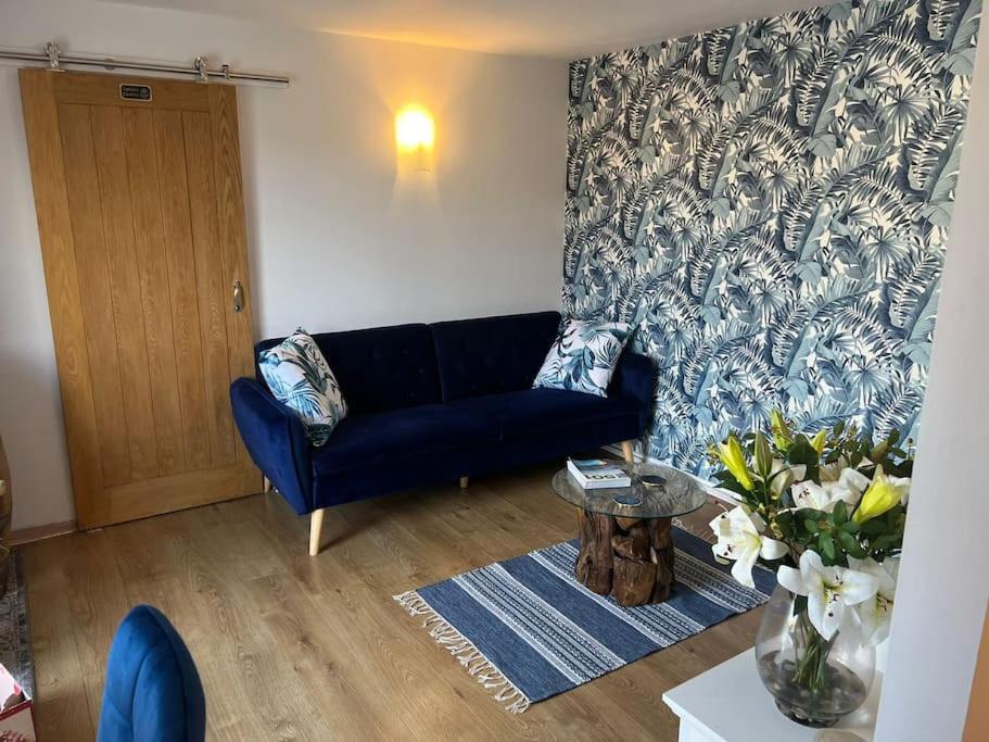 a living room with a blue couch and a table at Unique one bedroom guest house with free parking in Aldershot