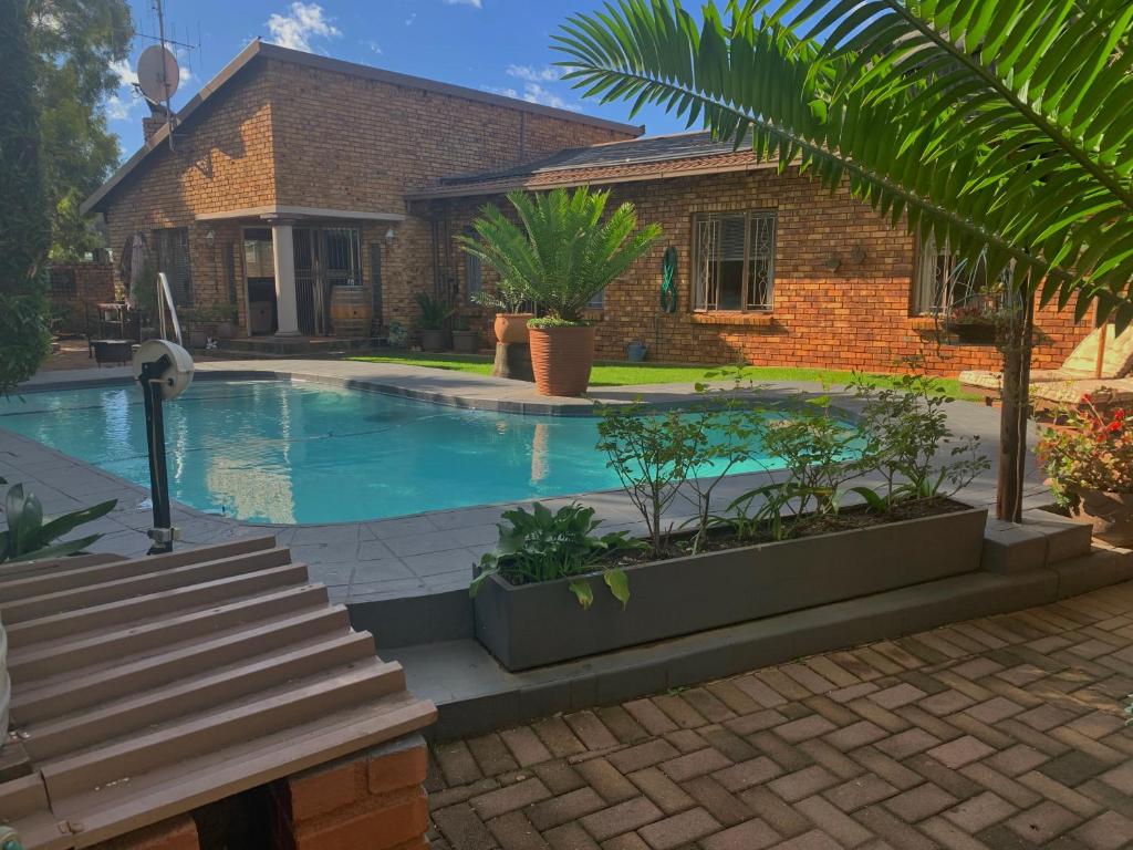 a swimming pool in front of a house at Dobbs Lodge in Centurion
