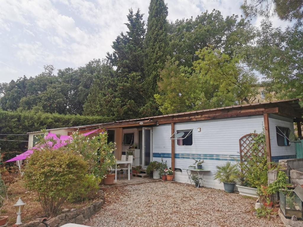 una pequeña casa blanca con patio y plantas en Mobil home hors camping, en Roquebrune-sur-Argens