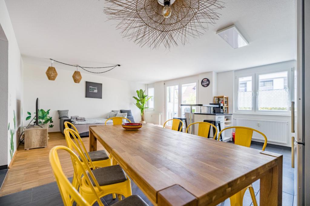 a dining room with a wooden table and yellow chairs at KAwaii- Big island in central location in Karlsruhe