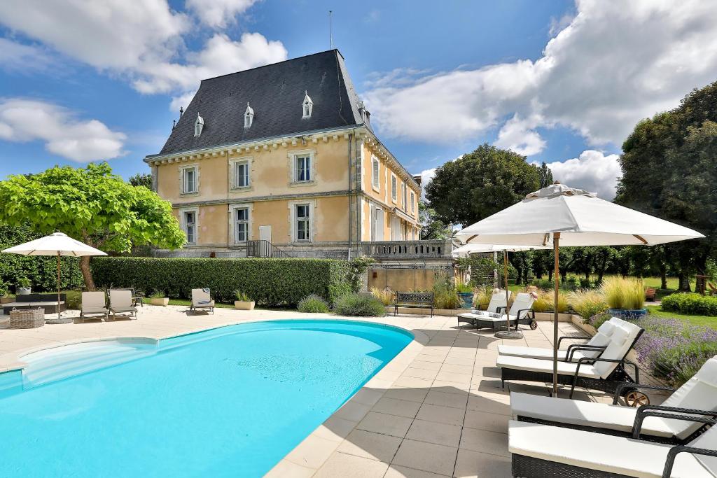 - une piscine avec des chaises et des parasols en face d'un bâtiment dans l'établissement Château de Villars, à Villars