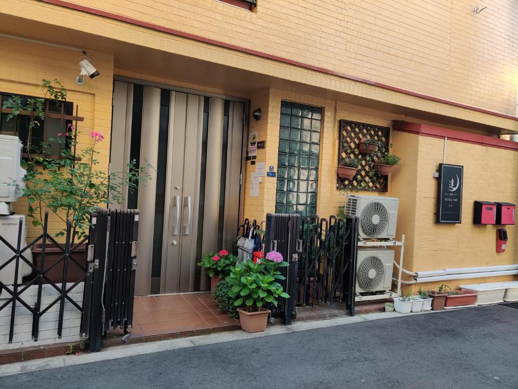 da inn في أوساكا: باب امام مبنى به سياج وزهور
