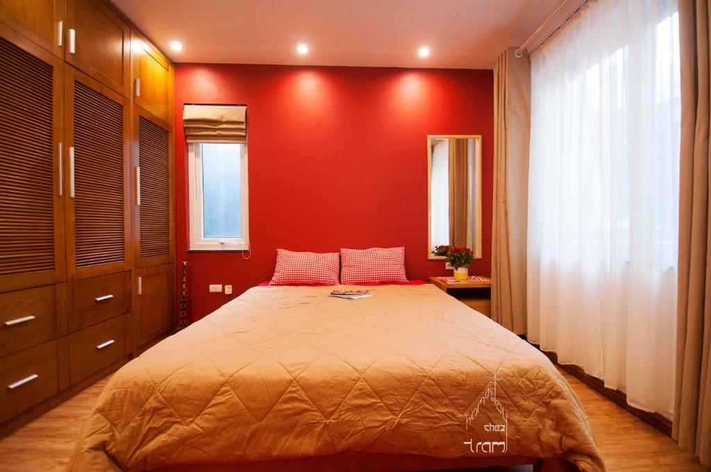 a bedroom with a large bed with a red wall at Chez Tram Homestay in Hanoi