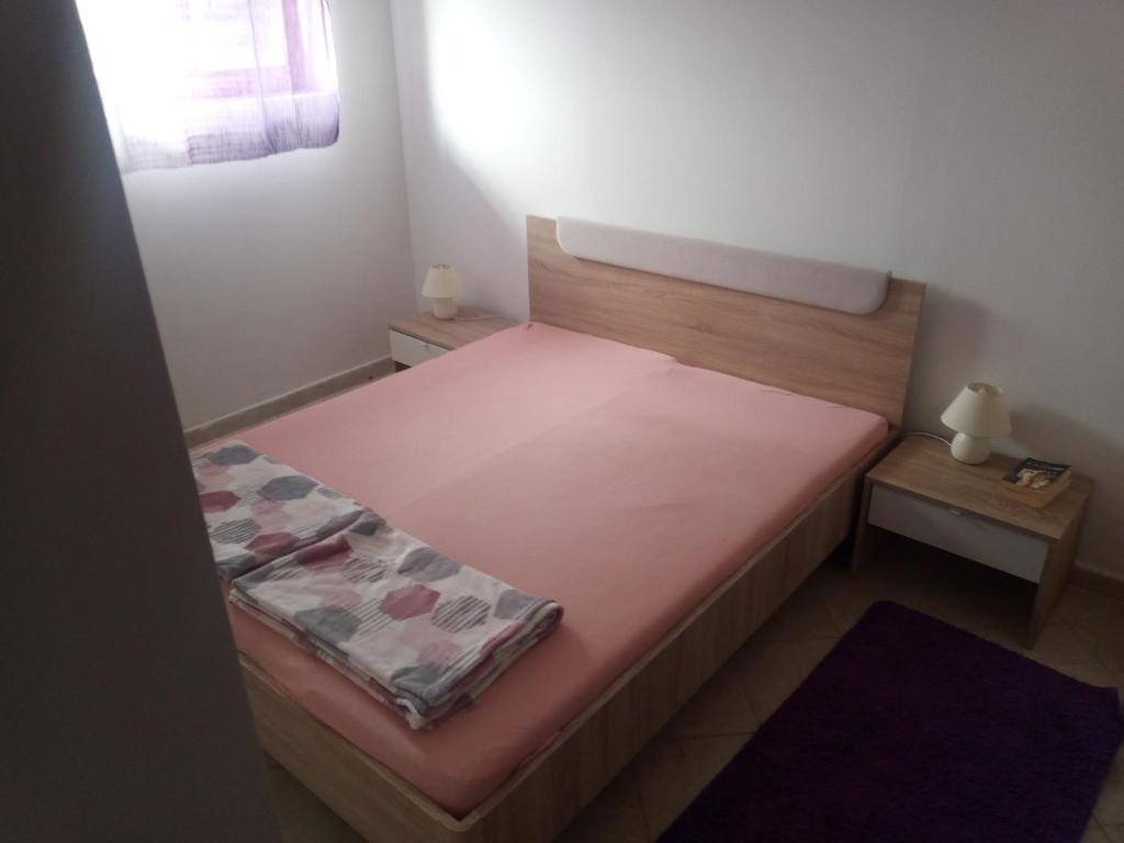 a small bedroom with a bed and two tables at Apartmani Rab - Adrijana & Aleksandra in Banjol