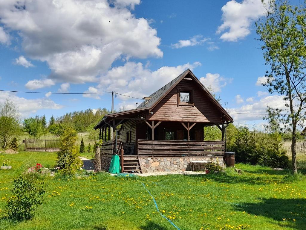 une petite maison en bois dans un champ d'herbe dans l'établissement Mazurska Niezapominajka, à Sajzy