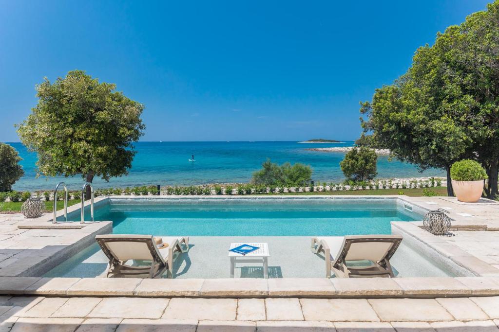 einen Pool mit Stühlen und das Meer im Hintergrund in der Unterkunft Luxury Glamping Beach Villas Porto Bus in Bale