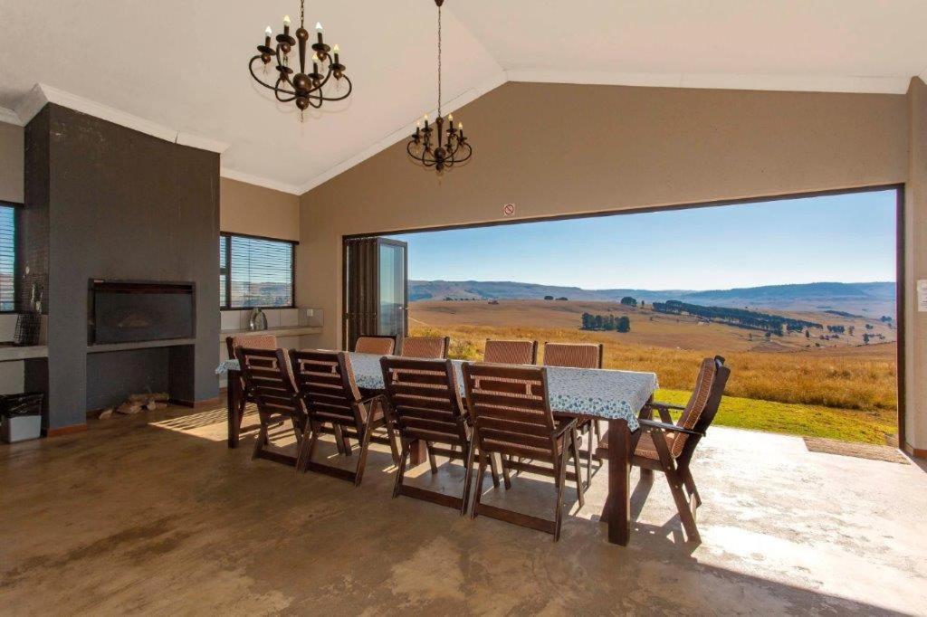 a dining room with a table and chairs and a large window at Ilanga Game & Fishing Lodge in Dullstroom