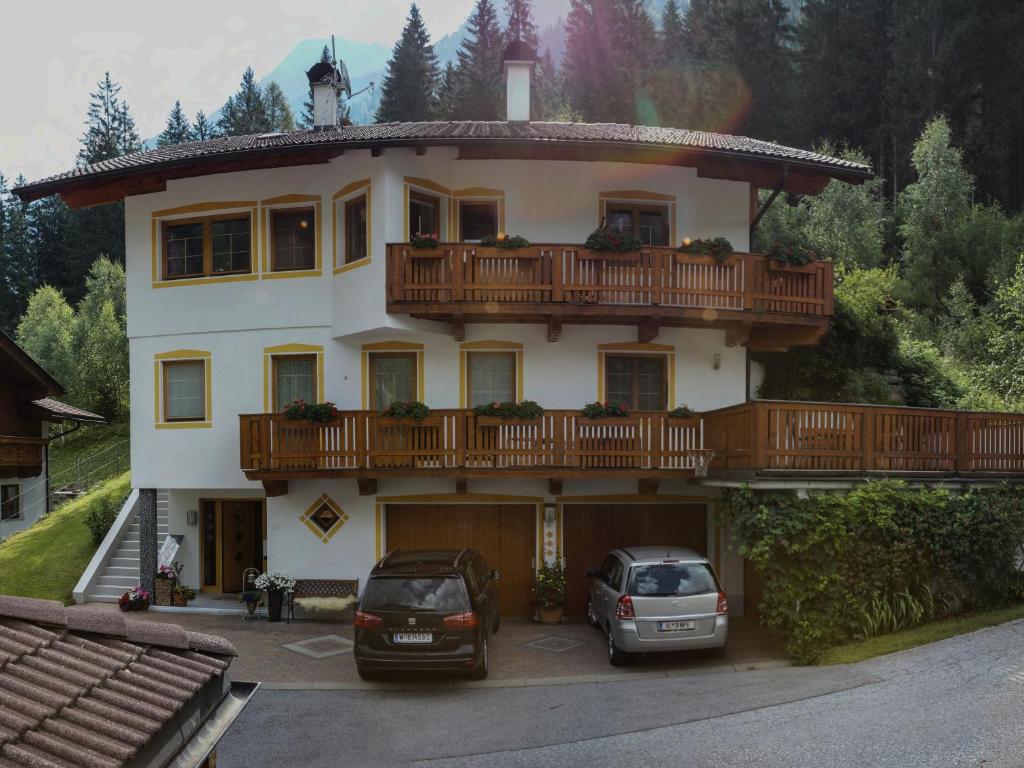 una casa grande con dos coches estacionados frente a ella en Haus Ferchl, en Neustift im Stubaital