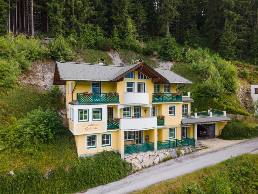 an aerial view of a yellow house on a hill at Landhaus Gabriele in Filzmoos