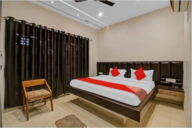 a bedroom with a large bed and a chair at Hotel Four Petals in Bhopal