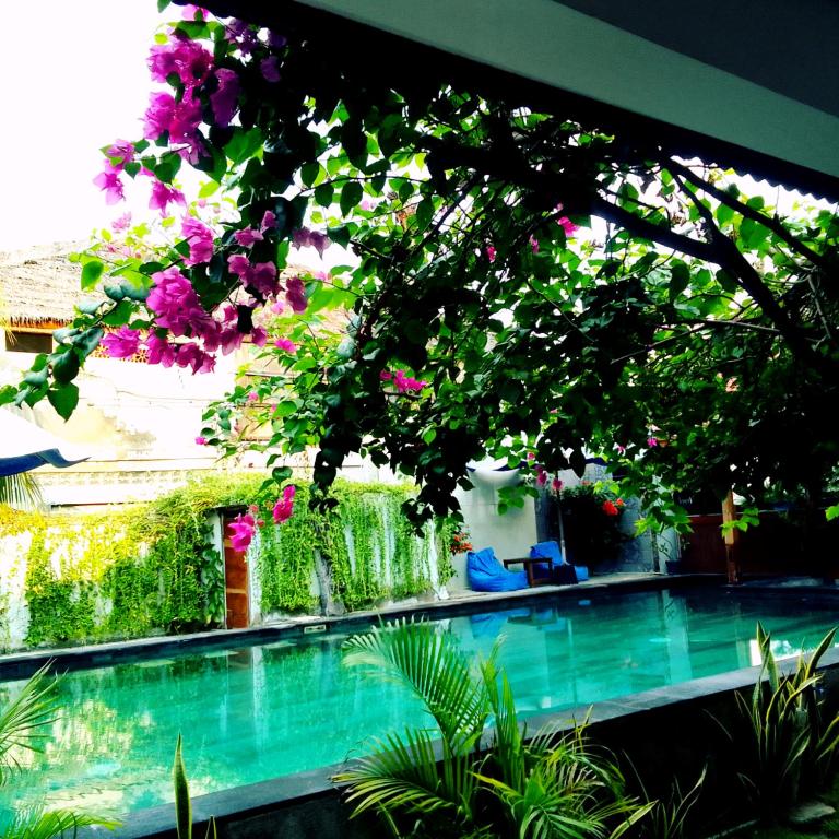 a swimming pool with flowers hanging from a building at Talent Sunset Villa in Gili Islands