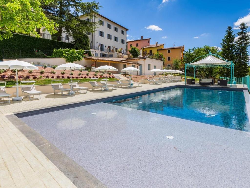 una piscina con sedie e ombrelloni accanto a un edificio di Cheerful holiday home in Serravalle di Chienti with garden a Serravalle di Chienti