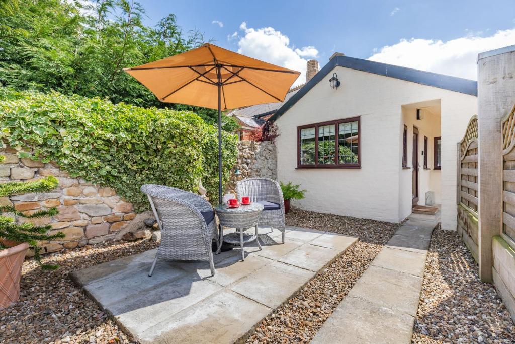 a patio with a table and chairs and an umbrella at Willow Cottage in Ulrome