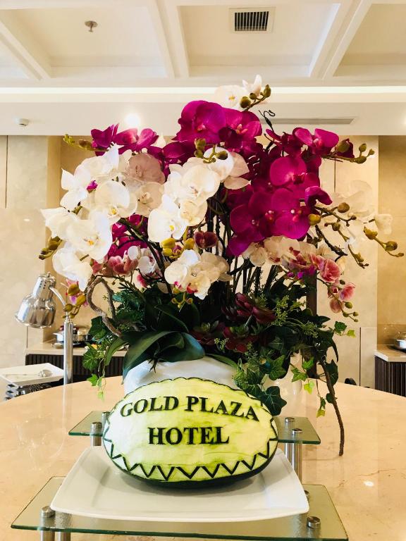 A large orchid arrangement with a Gold Plaza Hotel sign in a polished interior.