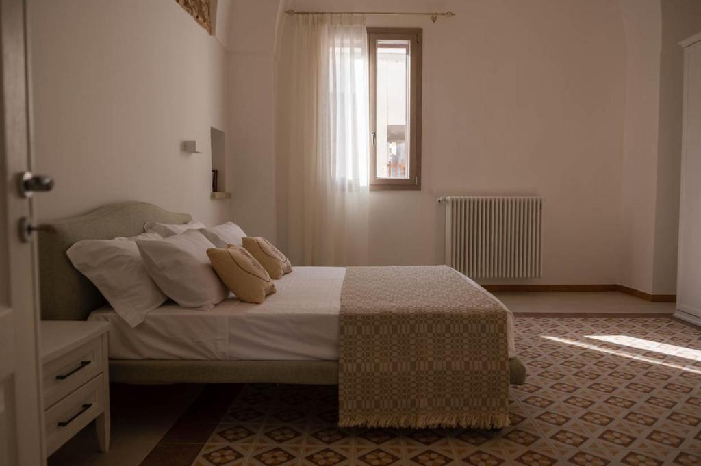 a bedroom with a bed with pillows and a window at Dimora Zio Vito in Patù