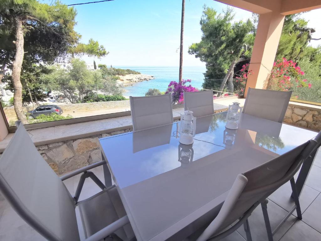 a white table and chairs with a view of the ocean at Archos Seafront Apartments in Porto Heli