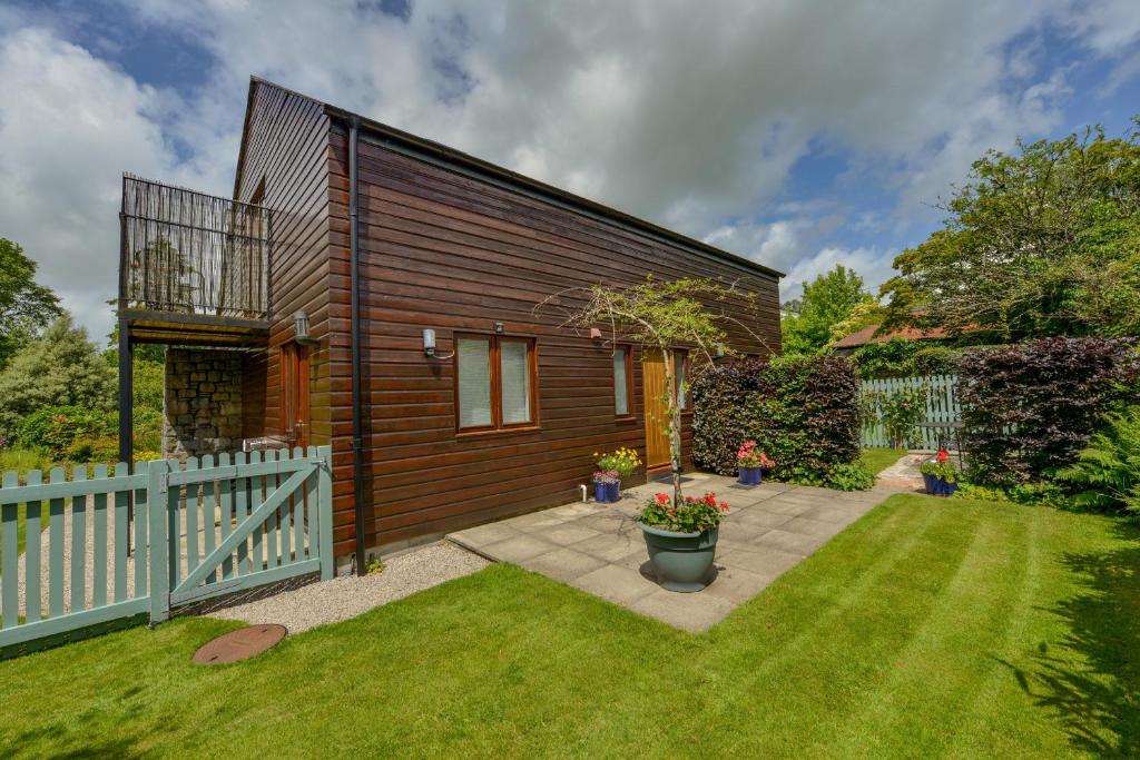 a small house with a fence and a yard at Cholwell Barn Apartment in Tavistock