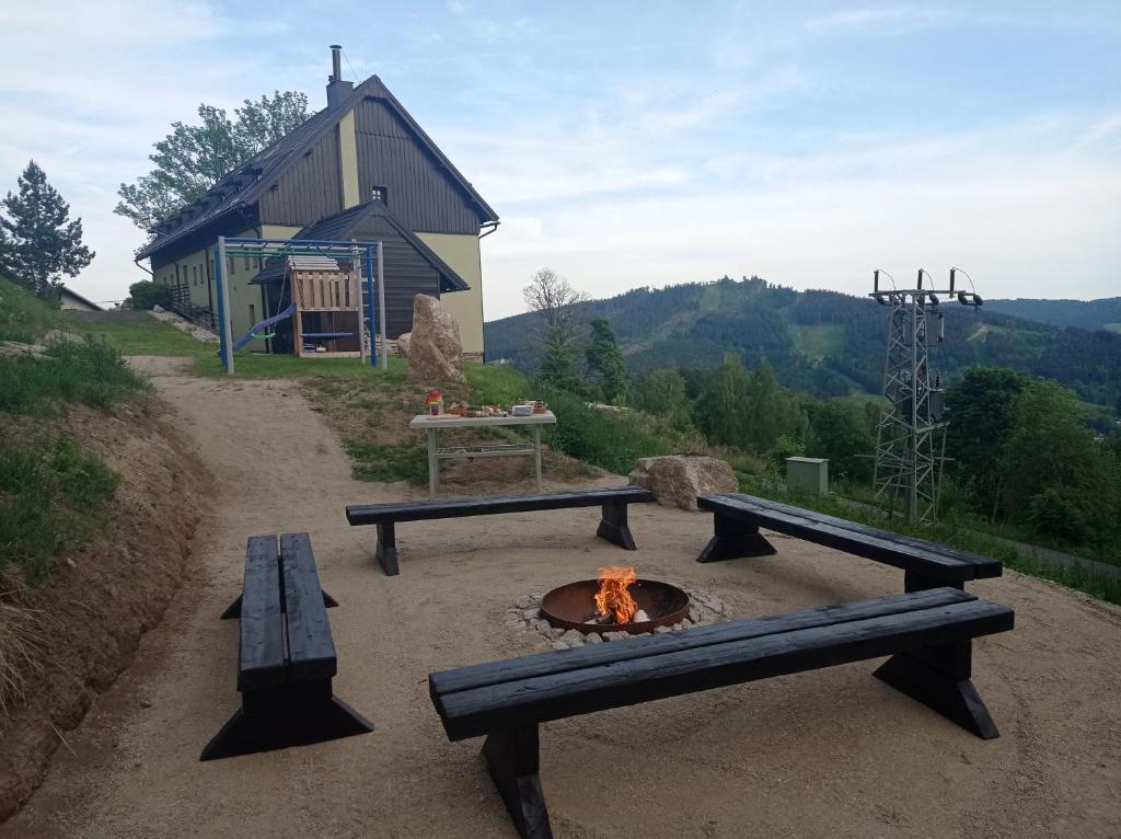 two benches and a fire pit with a building in the background at apartmány Kynast in Albrechtice v Jizerských horách