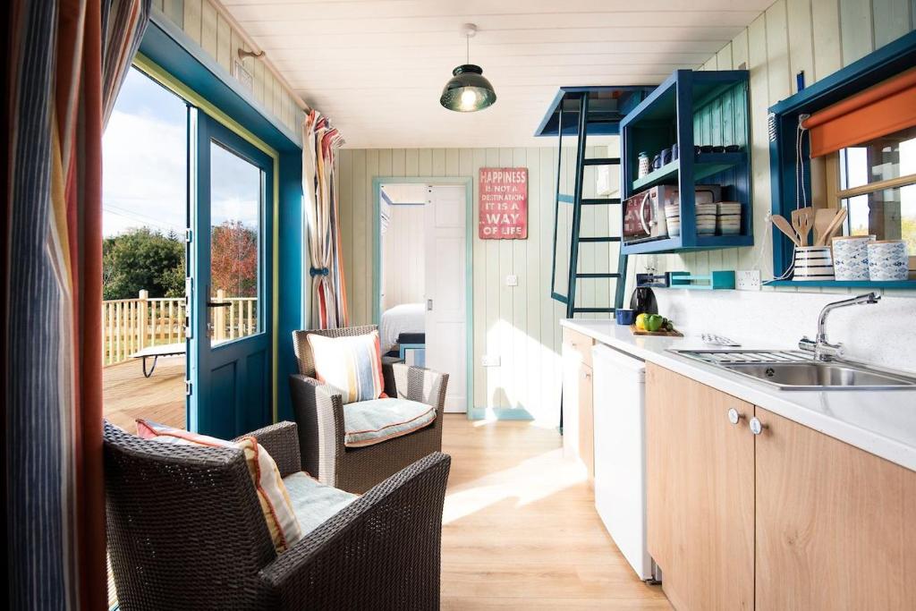 a kitchen with blue cabinets and chairs and a balcony at Berrington Beach Hut in Berwick-Upon-Tweed