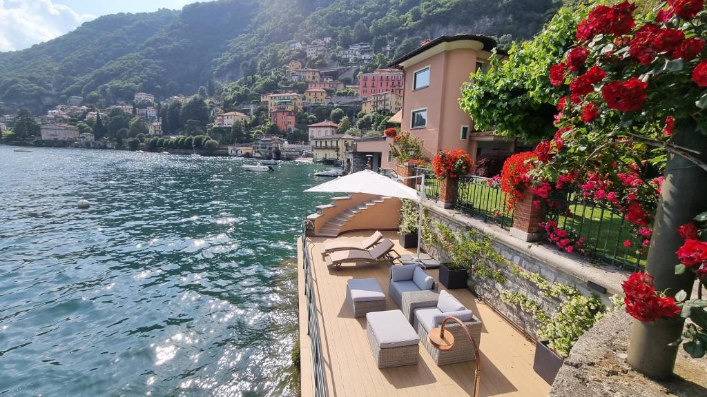 a group of chairs and an umbrella next to the water at Villa Noseda in Moltrasio
