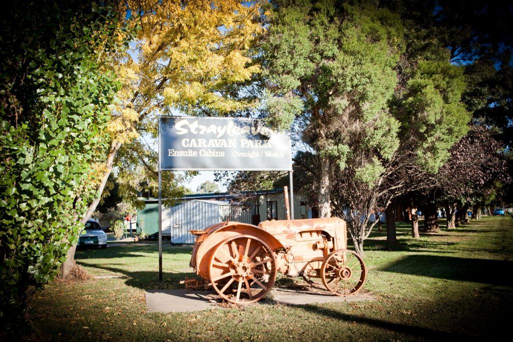 Ein Schild und ein alter Wagen im Park. in der Unterkunft Strayleaves Caravan Park in Shepparton