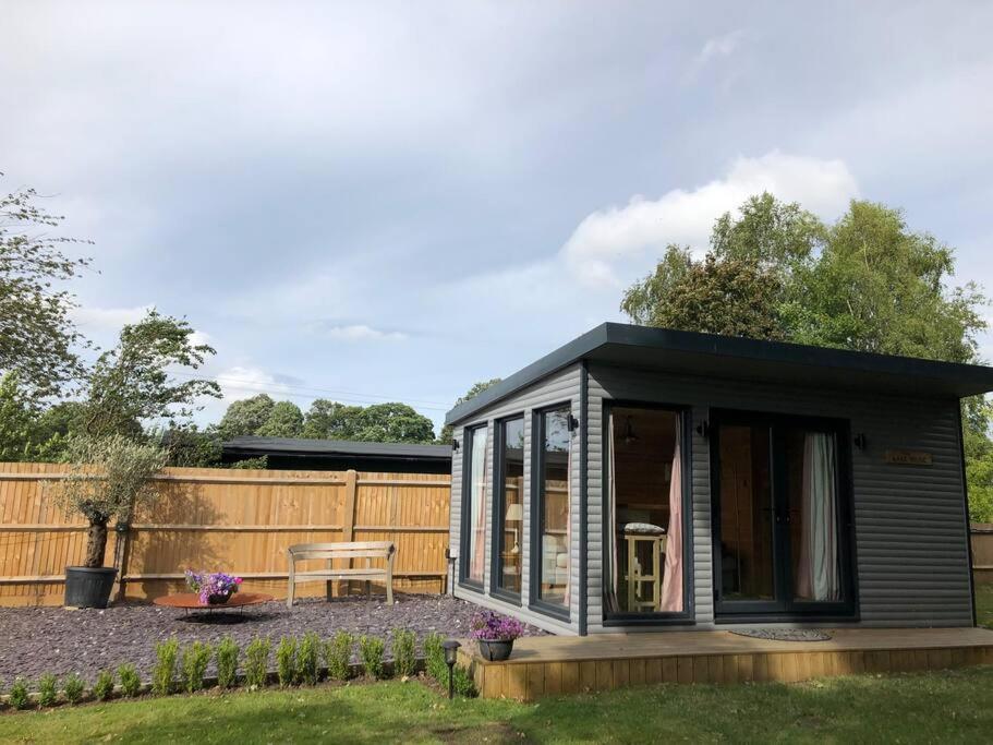 a small black shed with a table in a yard at Self Contained Garden Studio with stunning views in Sissinghurst