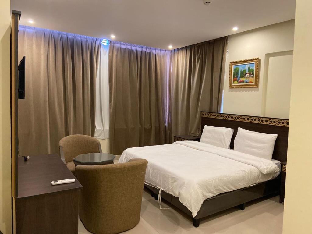 a bedroom with a bed and a table and chairs at Al Safiah Hotel in Al Madinah