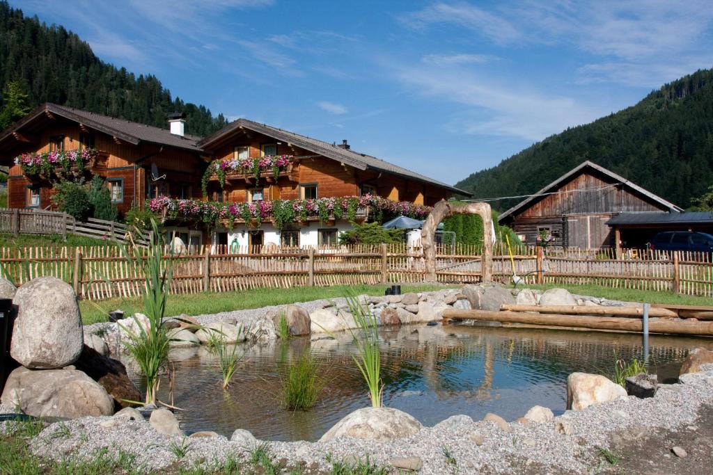 une cabane en rondins avec un étang en face de celle-ci dans l'établissement Gasthof Pesbichl, à Goldegg