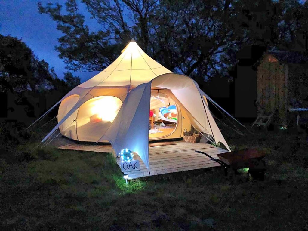 a tent with a deck in a field at night at Finest Retreats - Oak Lotus Belle Tent in Ilfracombe