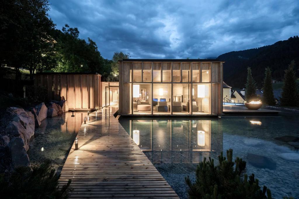 a house on a body of water with a dock at Adler Spa Resort Dolomiti in Ortisei