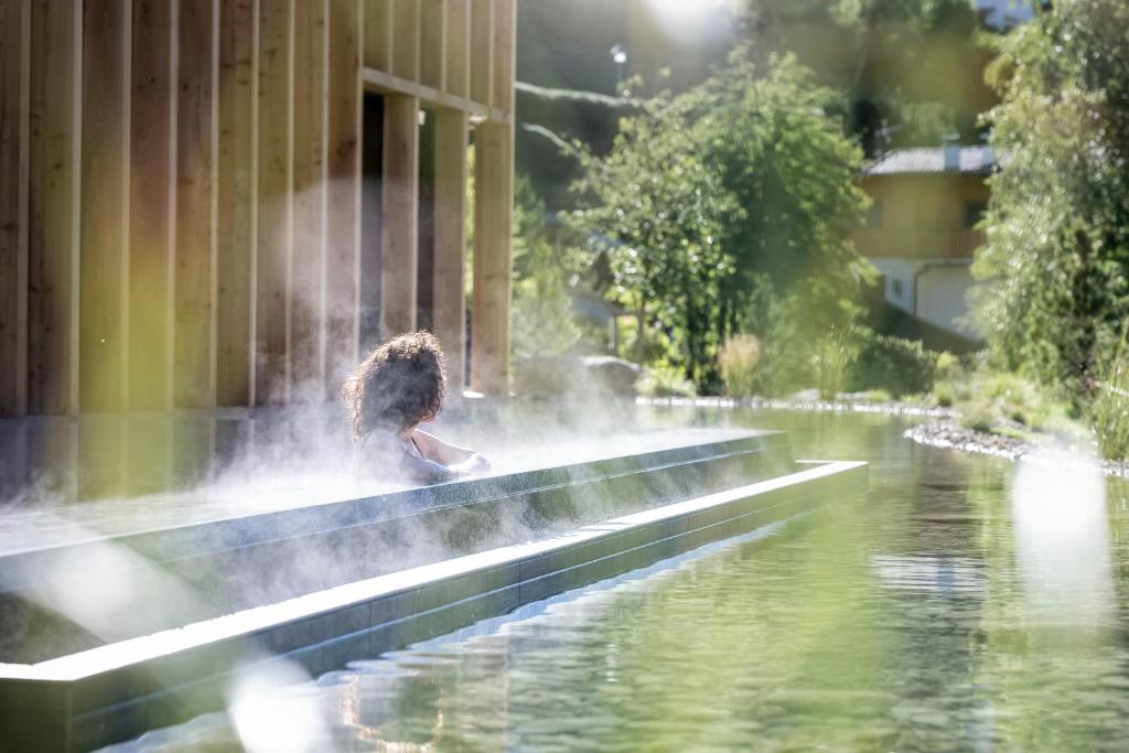 a young girl playing in a fountain in a pond at Adler Spa Resort Dolomiti in Ortisei
