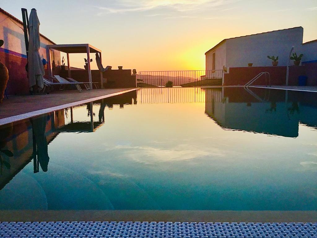 a swimming pool with the sun setting in the background at Villaggio Imbesi in Villa San Giovanni