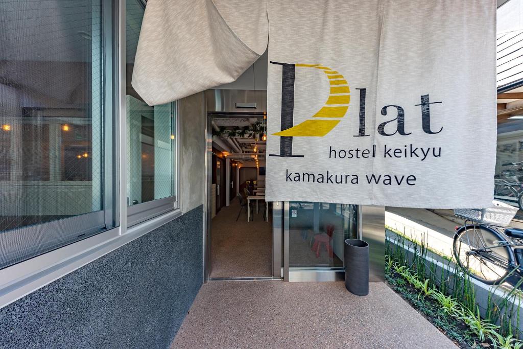 鎌倉市にあるplat hostel keikyu kamakura waveの建物の外に看板がぶら下がっている