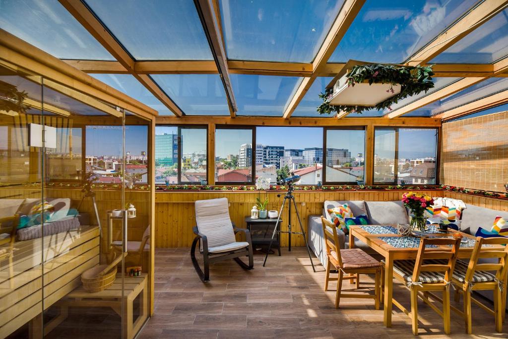 a conservatory with a table and chairs and windows at Bucharest Penthouse with Sauna and Terrace in Bucharest