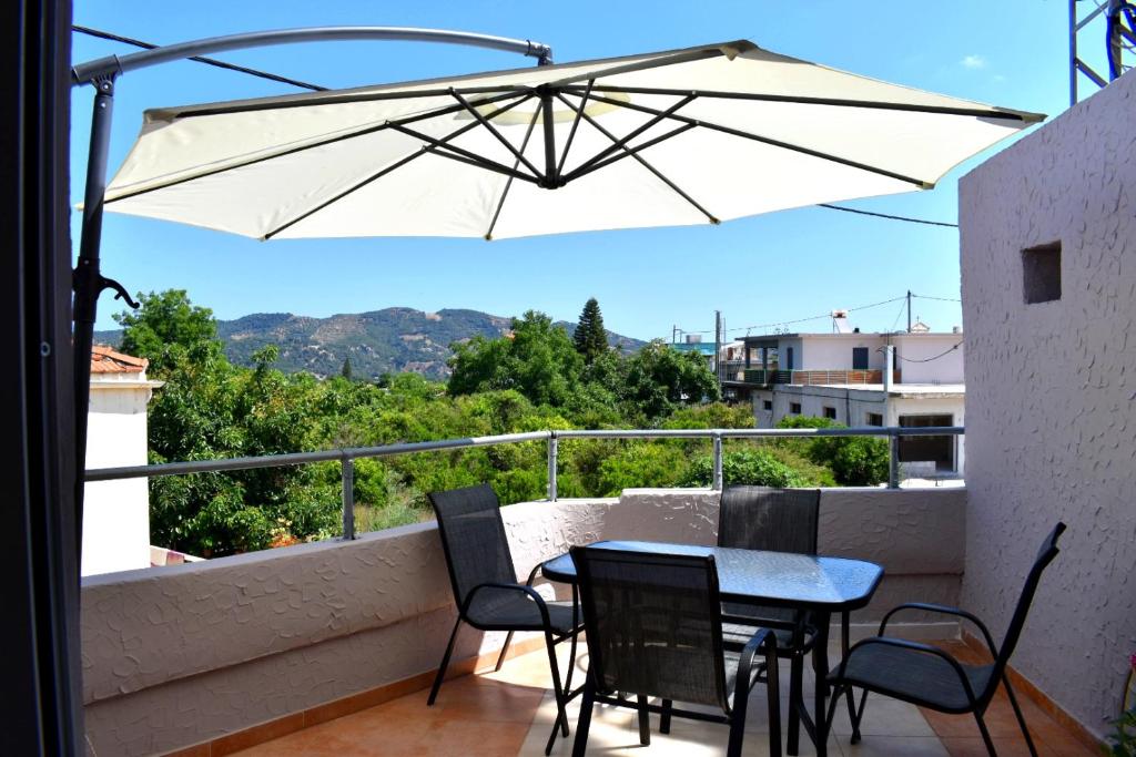 a table and chairs on a balcony with an umbrella at S&G HOME in Platanias