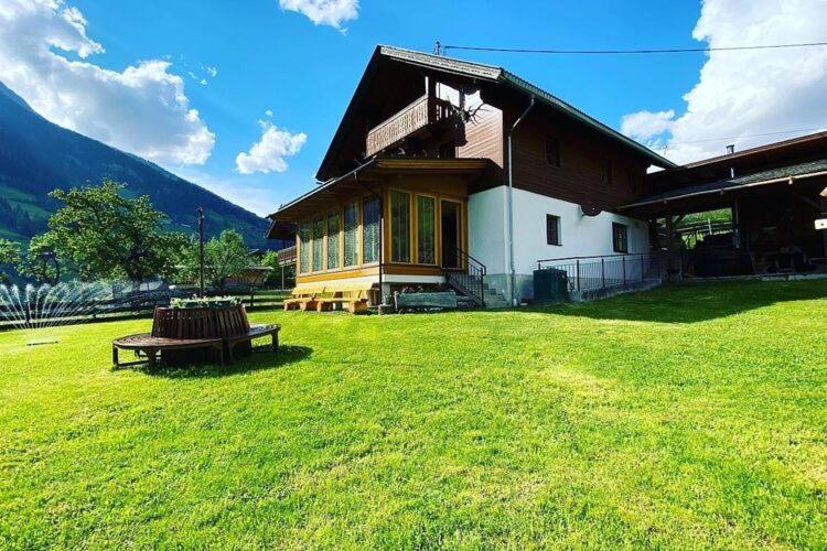 a house with a bench in front of a grass field at Chalet in Grosskirchheim in Carinthia with sauna in Großkirchheim