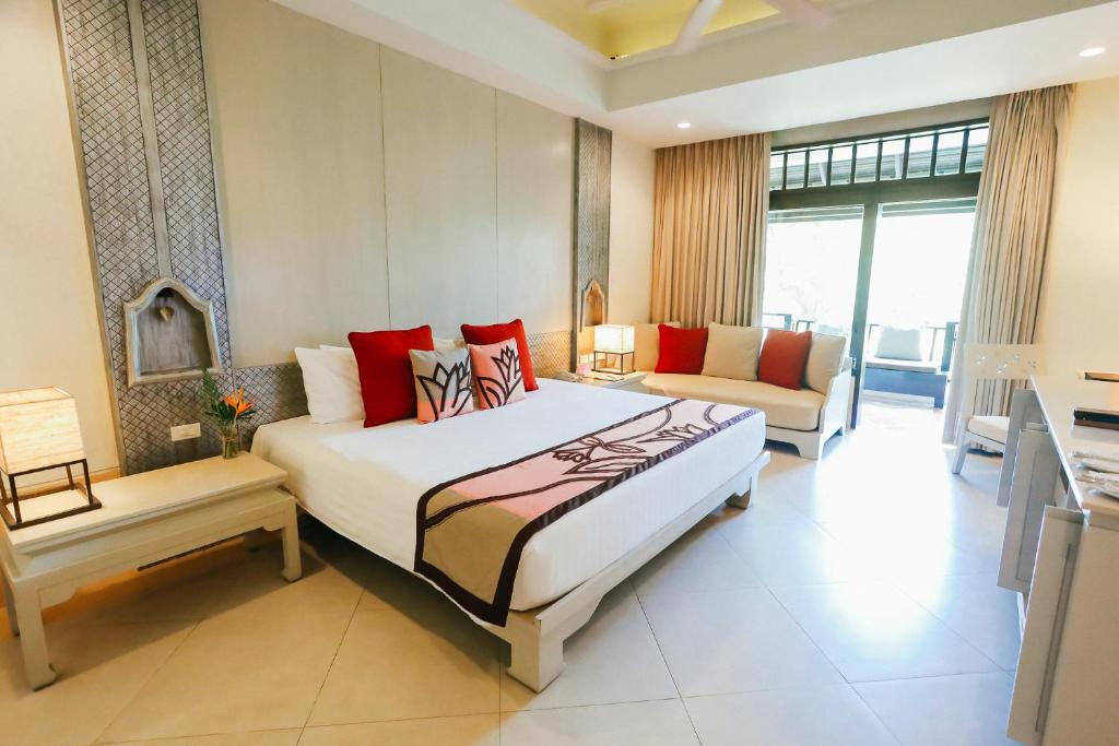 Melati Beach Resort & Spa في شاطئ تْشينغ مون: غرفة نوم بسرير كبير وغرفة معيشة