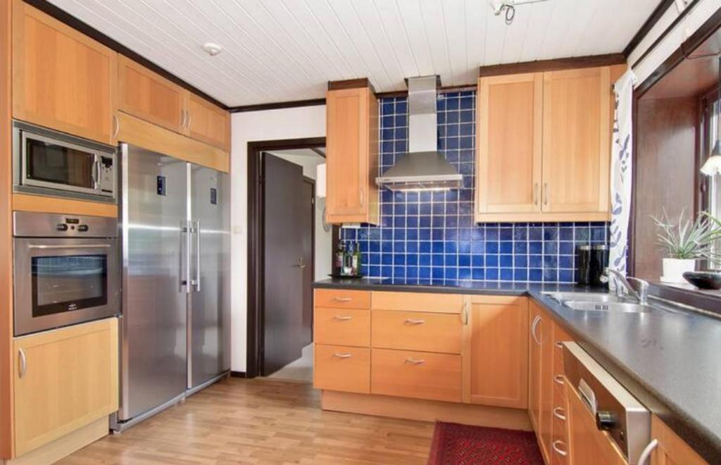 uma cozinha com armários de madeira e um frigorífico de aço inoxidável em Private Room in Shared House-Close to University and Hospital-1 em Umeå