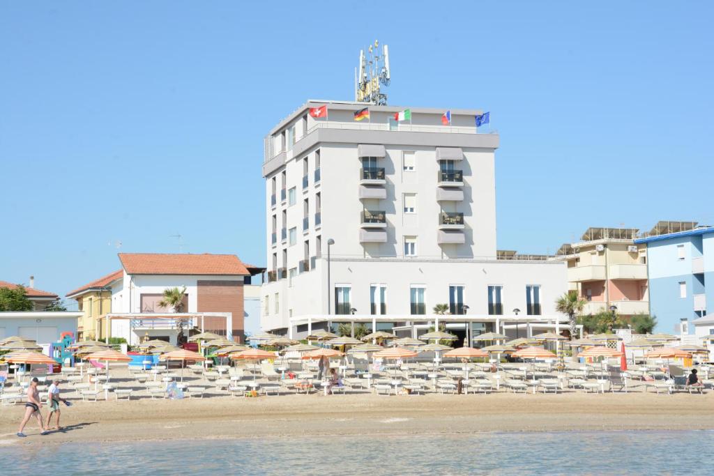 un edificio blanco en la playa con sombrillas en Hotel Caravel, en Marotta