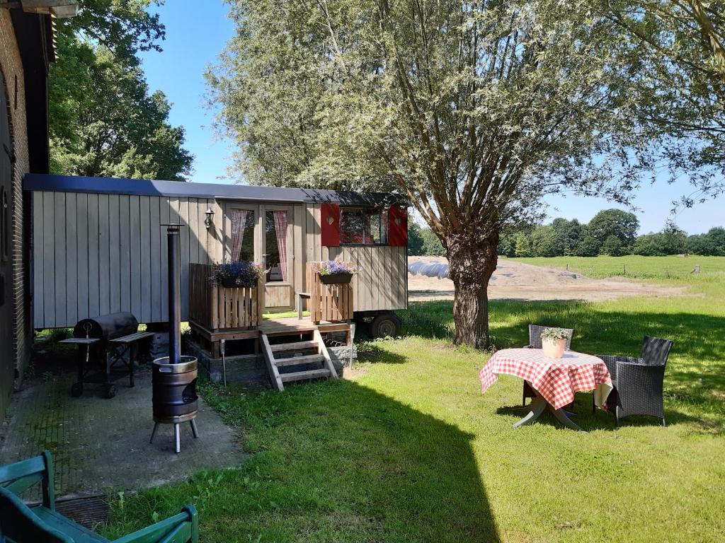 una cabaña con mesa de picnic y un árbol en Pipowagen 'klein Hoonhorst' en Putten