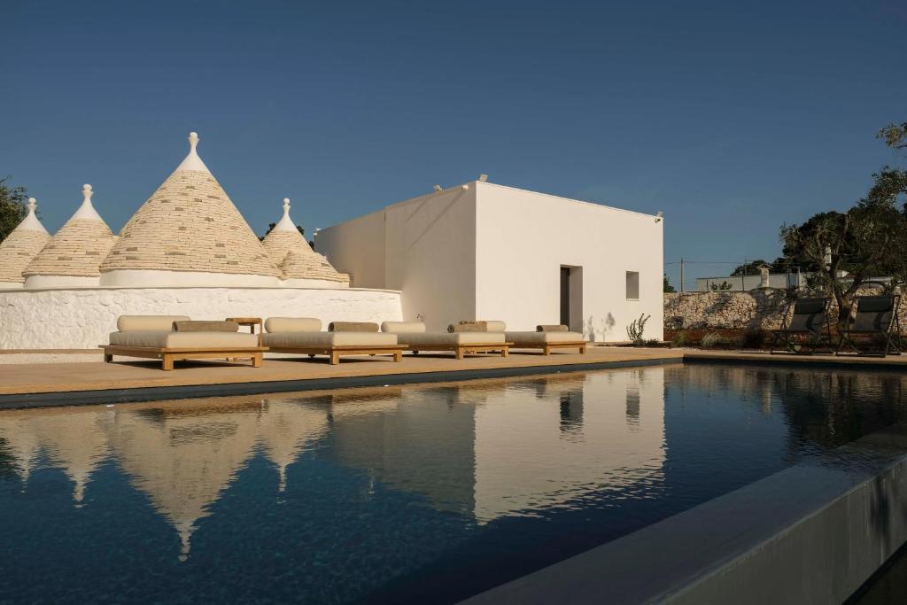 une piscine avec des chaises longues et un bâtiment dans l'établissement Trulli Petramyrta, à Ceglie Messapica